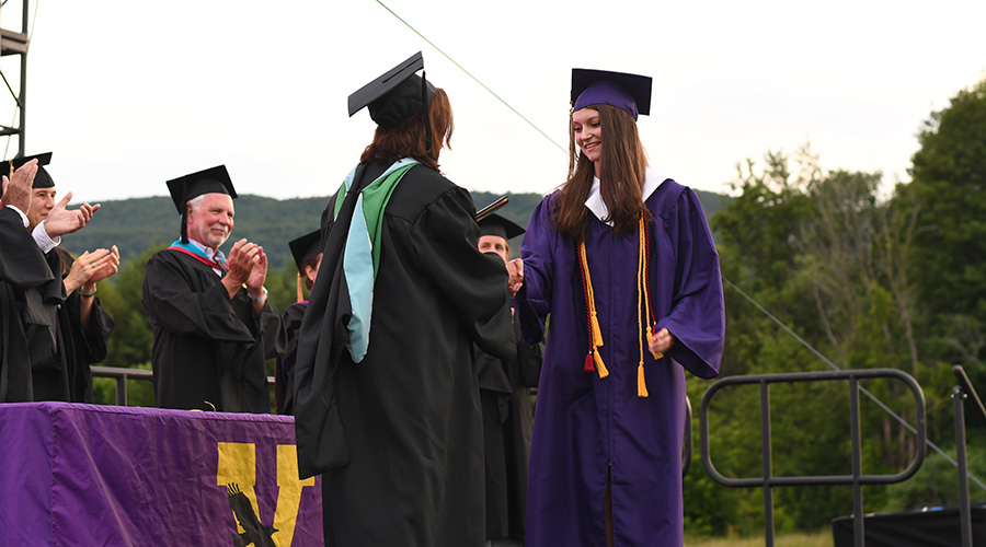 Student shaking hands and receiving diploma at graduation