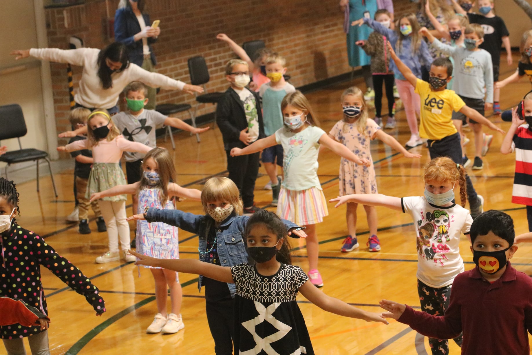 students in gym with their arms up swaying