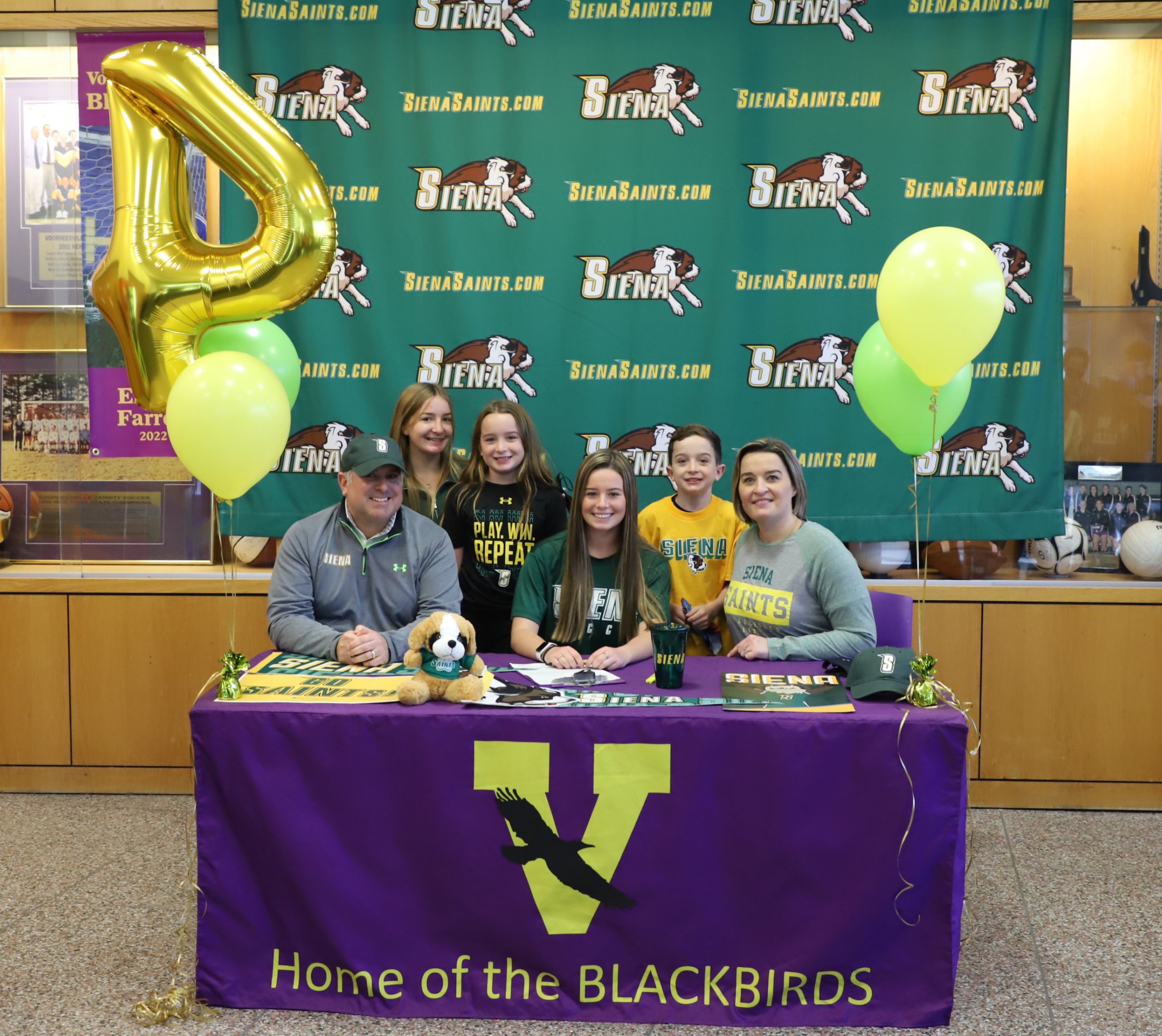 five family members standing around student-athlete signing letter of intent to play Division 1 soccer