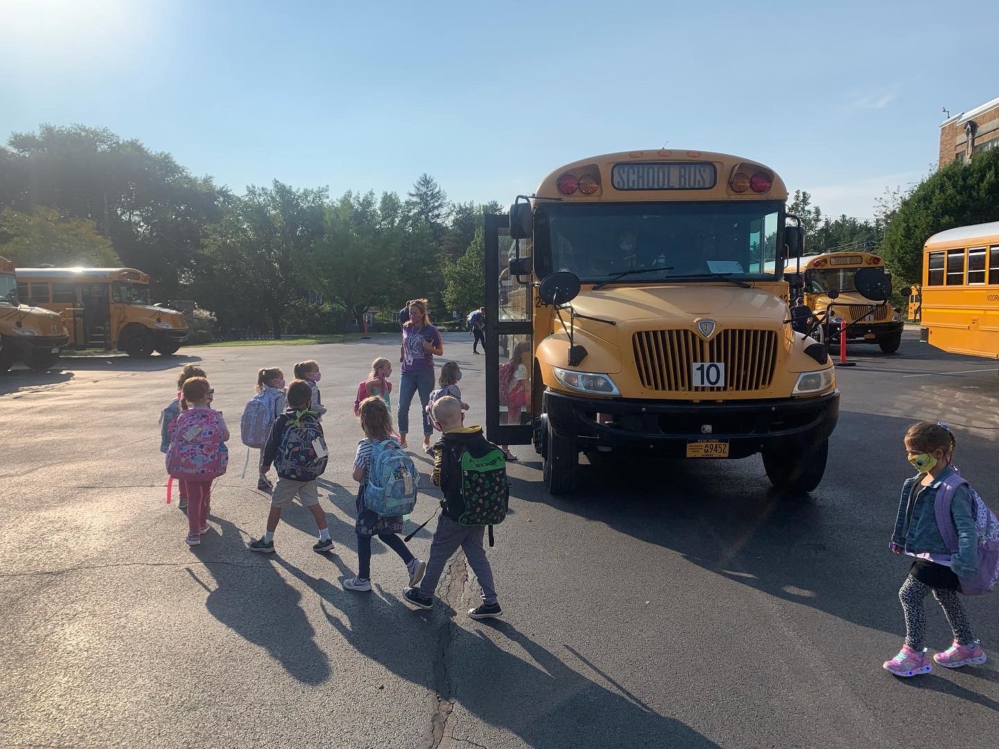students wearing backpacks walking to their school bus