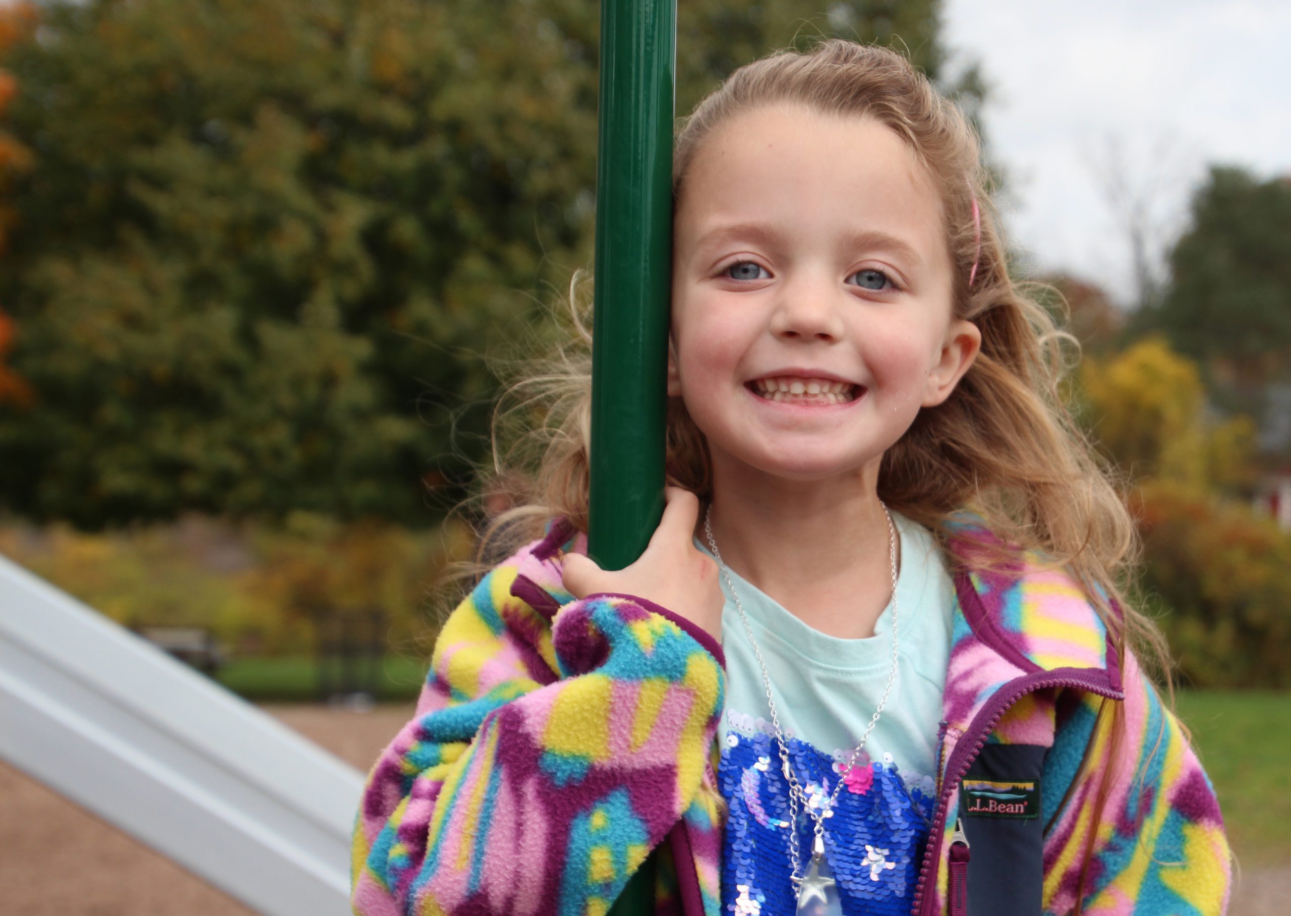 An elementary student smiles for a photo outside