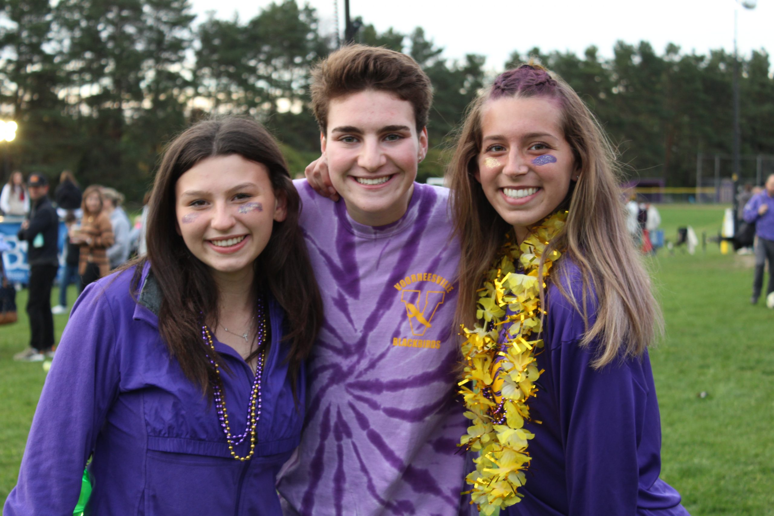 A photo of three highschoolers posing outside in festive VCSD clothes for Homecoming Weekend