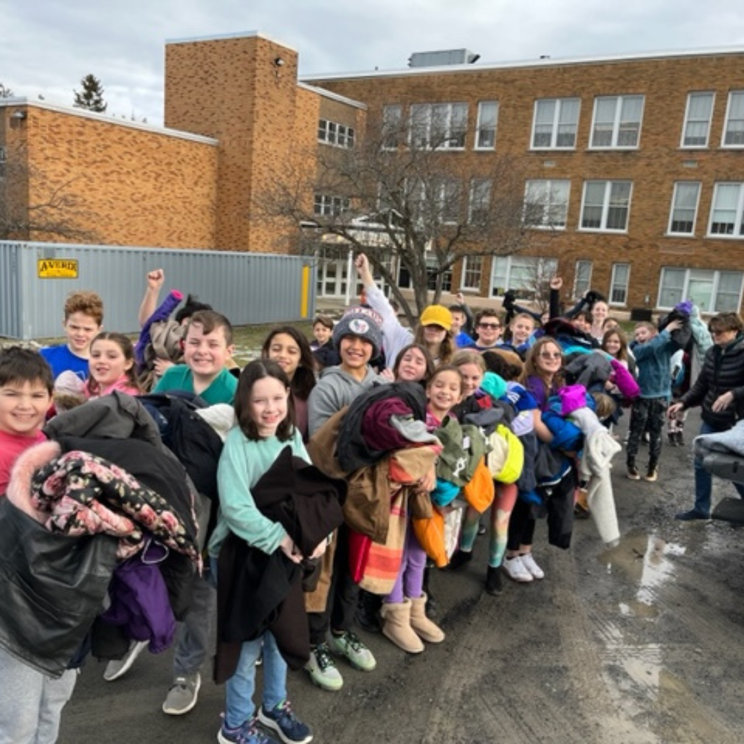 children stand in line holding coats