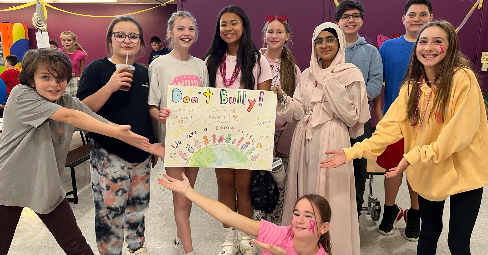 10 students stand around a handmade poster that says "Don't bully. We are a community."