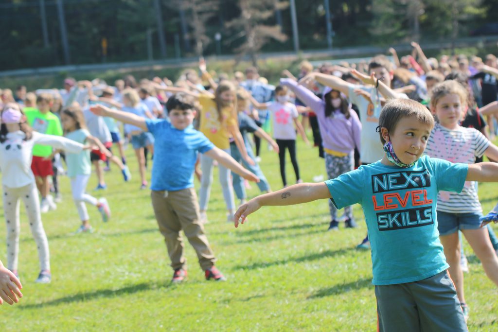 students standing outside with their hands in the air dancing