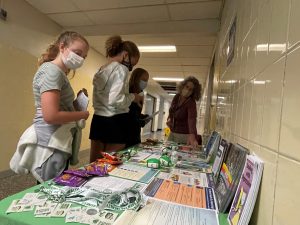 three students looking at a table filled with suicide prevention information and a health rep is explaining issues to them