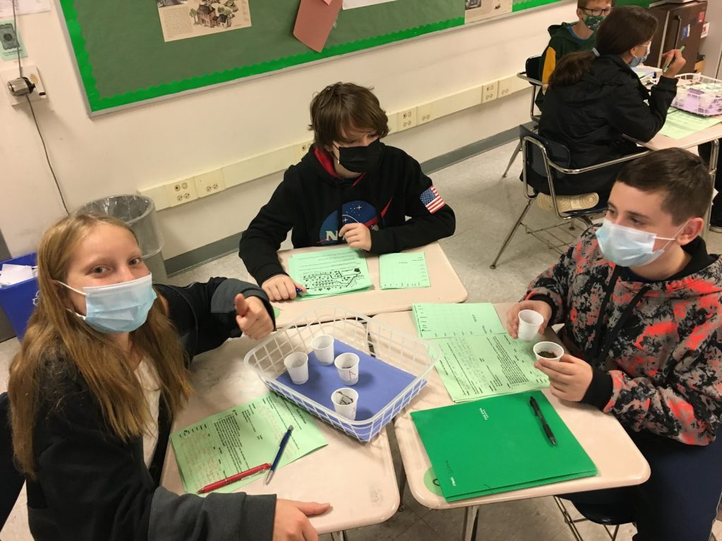 students sitting at table doing a forensic science experiment 