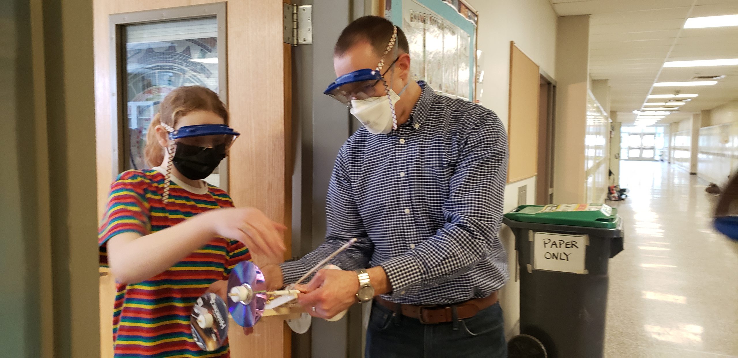 teacher and student wearing goggles and holding mousetrap cars