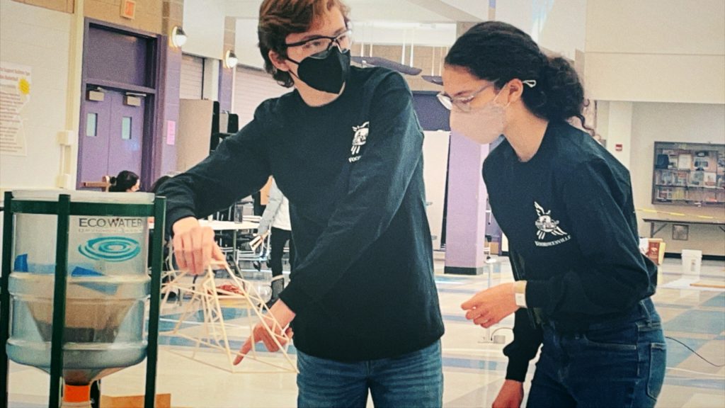 one student holding sticks and the other student preparing to make a move