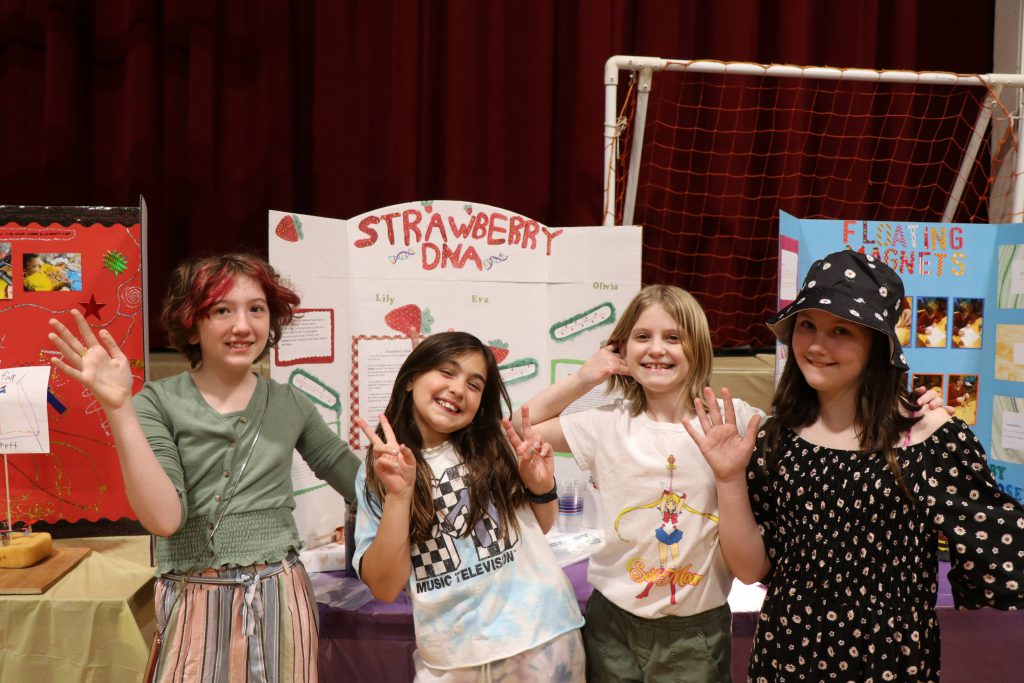 four students pose by DNA of strawberries project