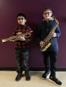 one student holds a trumpet the other a sax