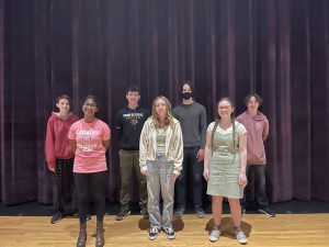 seven chorus students standing on a stage in front of a purple curtain
