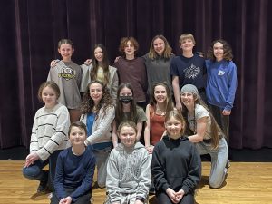 14 chorus students standing on stage smilin