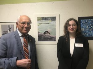 students stands next to her photograph and congressman stands on the other side