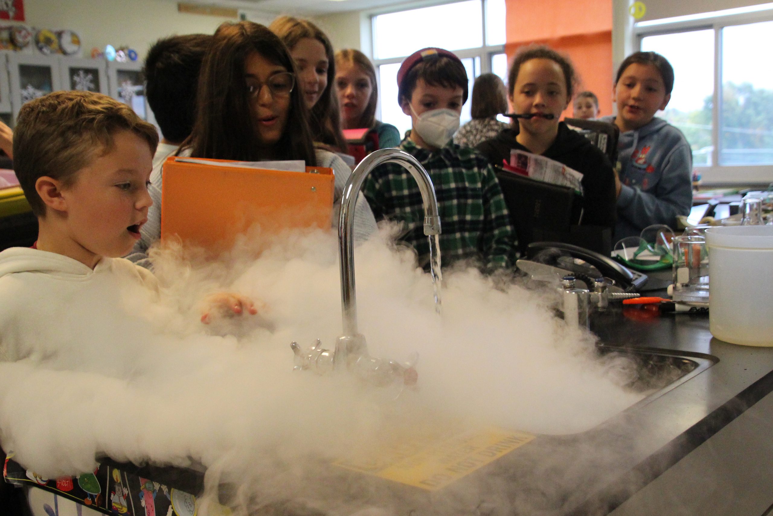 Middle school students stand next to a steamy science project.