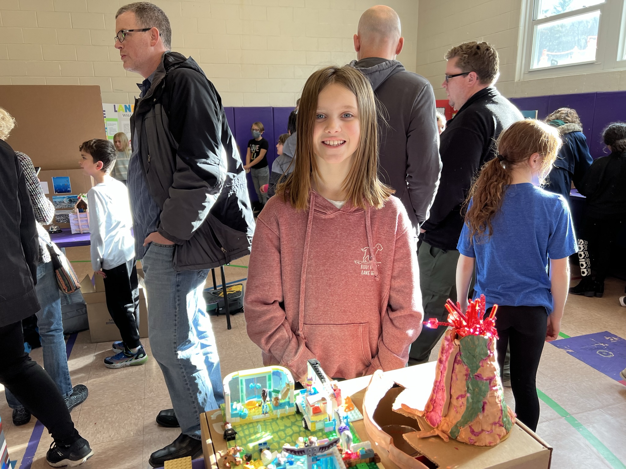 4th Grade Natural Disaster Project Presentation.  Student stands in front of model volcano.  Parents are in the background.