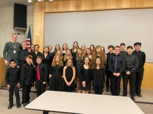 Members of the middle school chorus stand together wearing semi-formal attire at SCMA performance.