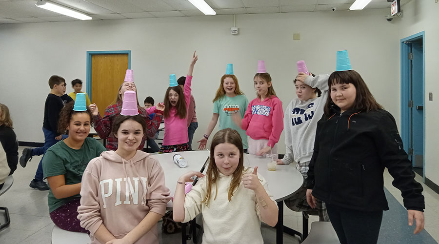 A group of Grade 6 girls balance cups on their heads.