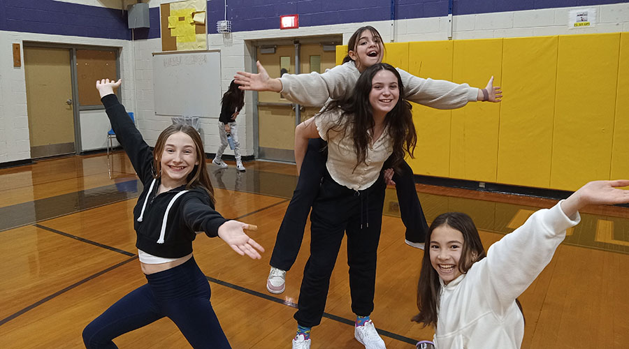 Four girls smile and pose in gym.