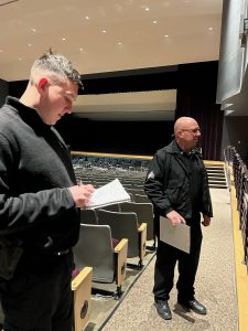 Two officers conduct a safety audit in auditorium.