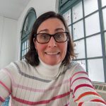 Woman wearing stripped sweater and glasses smiles at camera