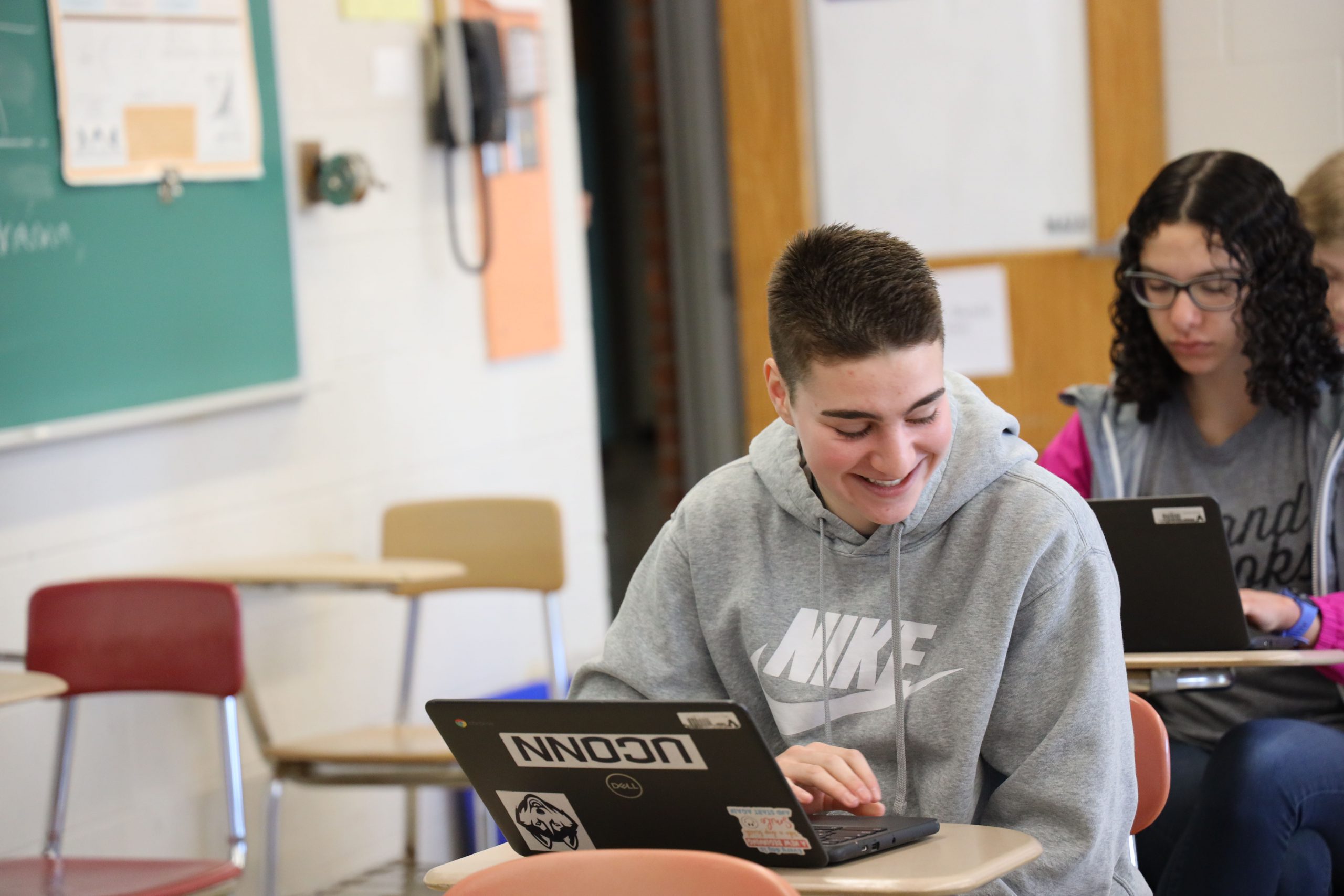 High School Students in class with teacher in background.