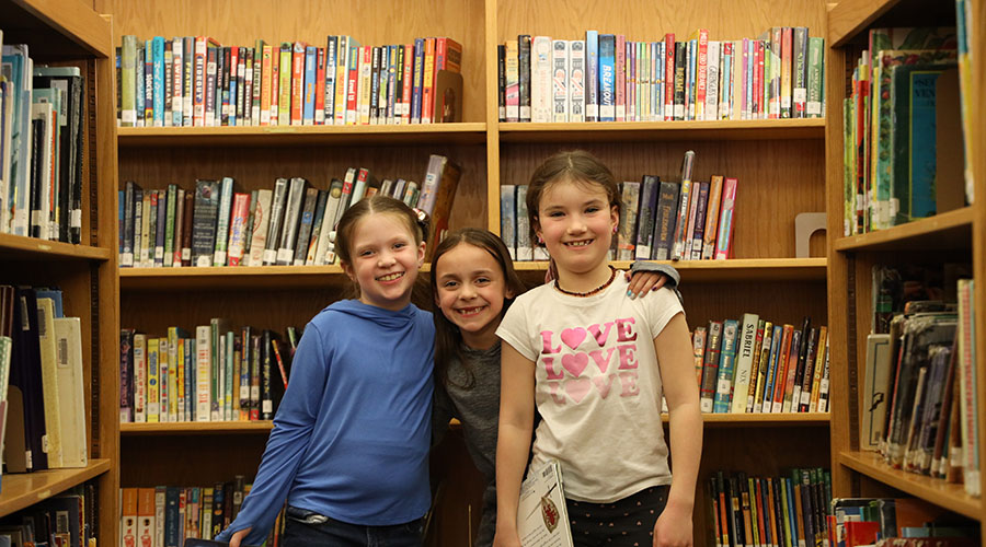 three voorheesville smiling elementary students in library f
