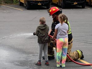 Firefighters with students using a hose.