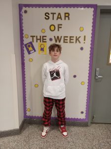 Griffin Owen stands in front of Star of the Week bulletin board.