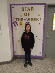 Nico Tillou stands in front of Star of the Week bulletin board.