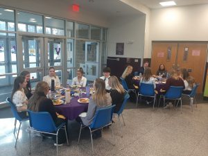 High school students dressed in business attire meet with members of the FBI around a lunch table.