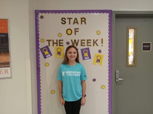 Middle school student stands in front of Star of the Week bulletin board.