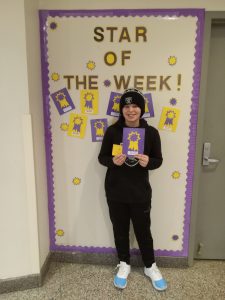 Mateo P. stands in front of Star of the Week bulletin board.