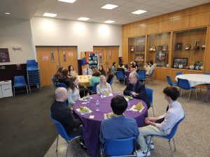 Students speak with adults at round tables .