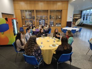 Students speak with adults at round tables .