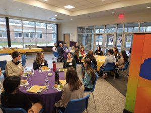 Students speak with adults at round tables .