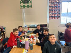 Students at table with pizza.