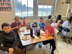 Students at table with pizza.