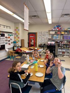 Students at table with pizza.