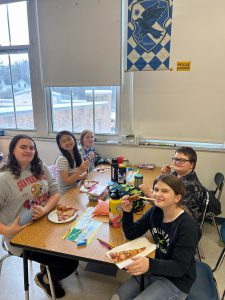 Students at table with pizza.