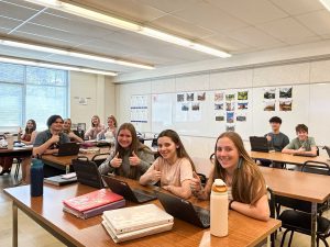 Students give a thumbs up from their seats in high school classroom