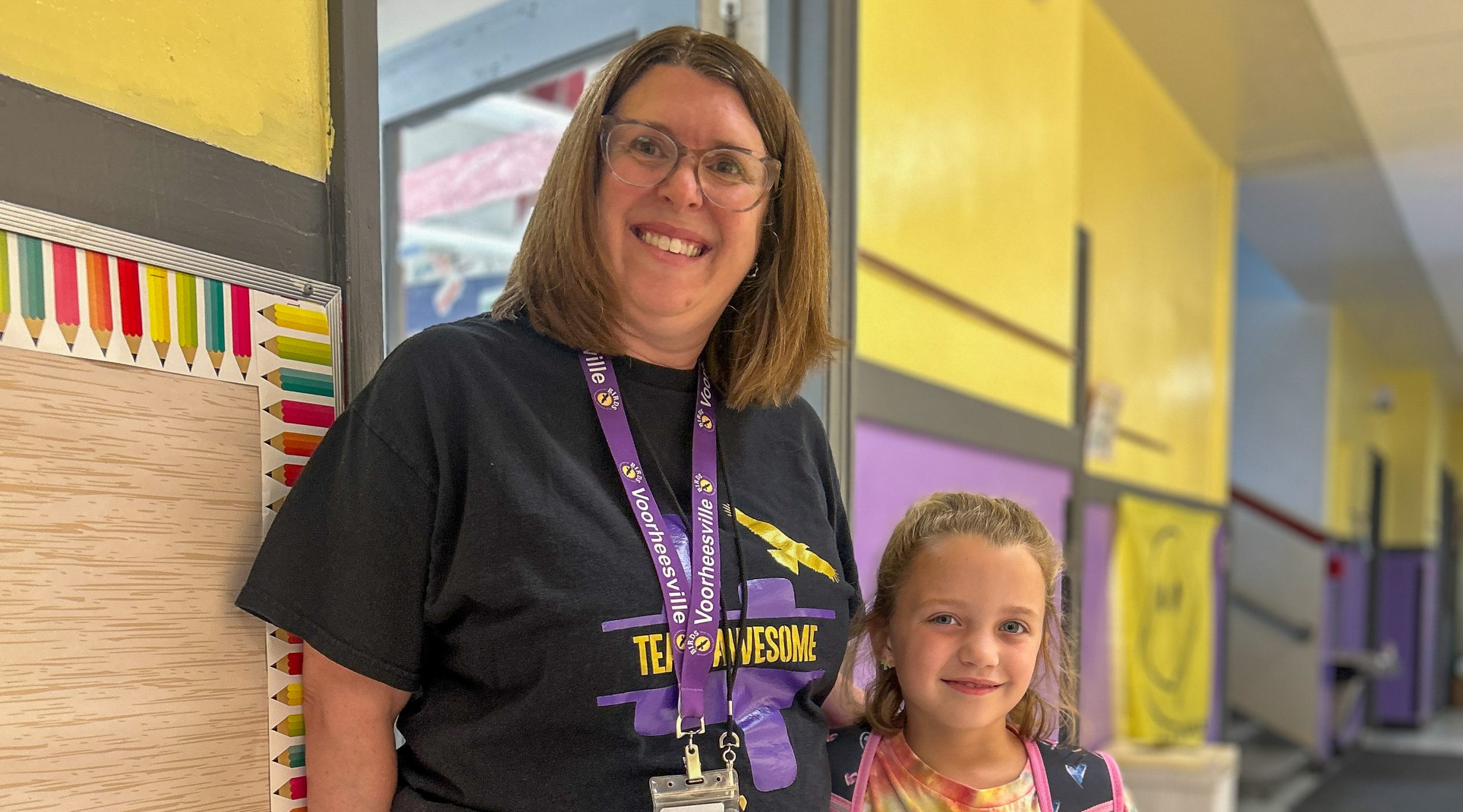 Teacher and elementary students in hallway.