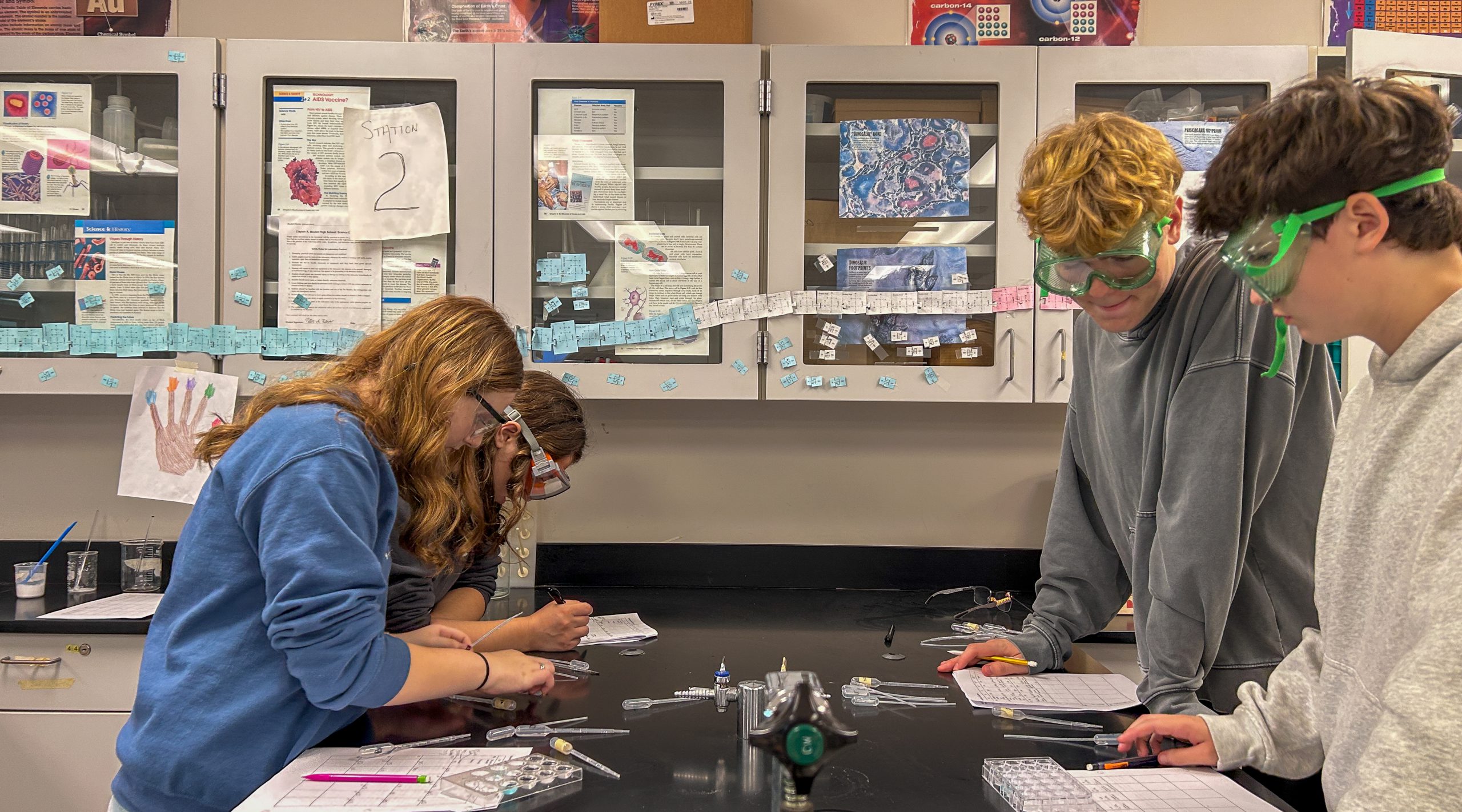 Four high school students conducting lab experiments in classroom.