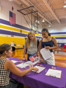 Adult talks with two students at Volunteer Fair.