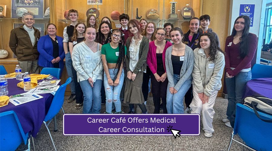 Group of high school students and adults standing together in a school lobby area with sports memorabilia displayed in a case behind them. Tables with informational materials and refreshments are set up nearby. A banner on the image reads, ‘Career Café Offers Medical Career Consultation