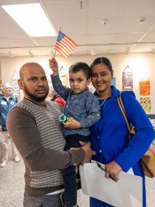 A young child holds an American flag while standing with family members following a naturalization ceremony.